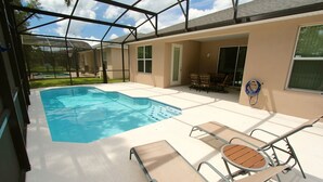 A covered swimming pool area with lounge chairs and a patio table. - Crystal Cove 929 (Kissimmee)