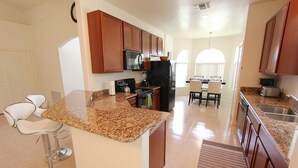 A modern kitchen with granite countertops, stainless steel appliances, and wooden cabinets. - Crystal Cove 929 (Kissimmee)