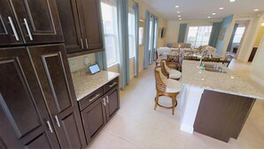 Una cocina moderna con gabinetes de madera oscura, encimera de granito y una isla central con taburetes de bar.