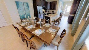 Comedor con una mesa larga dispuesta para seis personas, rodeada de sillas de madera.
