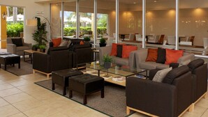 Un salon moderne avec des canapés, une table basse et une grande fenêtre donnant sur un paysage verdoyant.