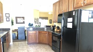 A kitchen with wooden cabinets, a black refrigerator, a stove, and a sink. - Crystal Cove 4768 (Kissimmee)