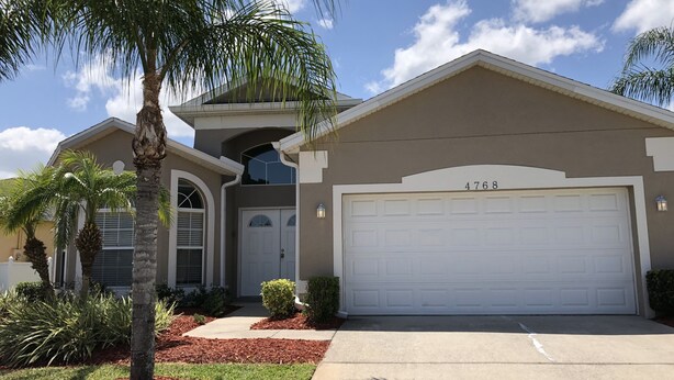 A two-story house with a garage, numbered 4768, surrounded by a landscaped garden with palm trees and shrubs. - Crystal Cove 4768 (Kissimmee)