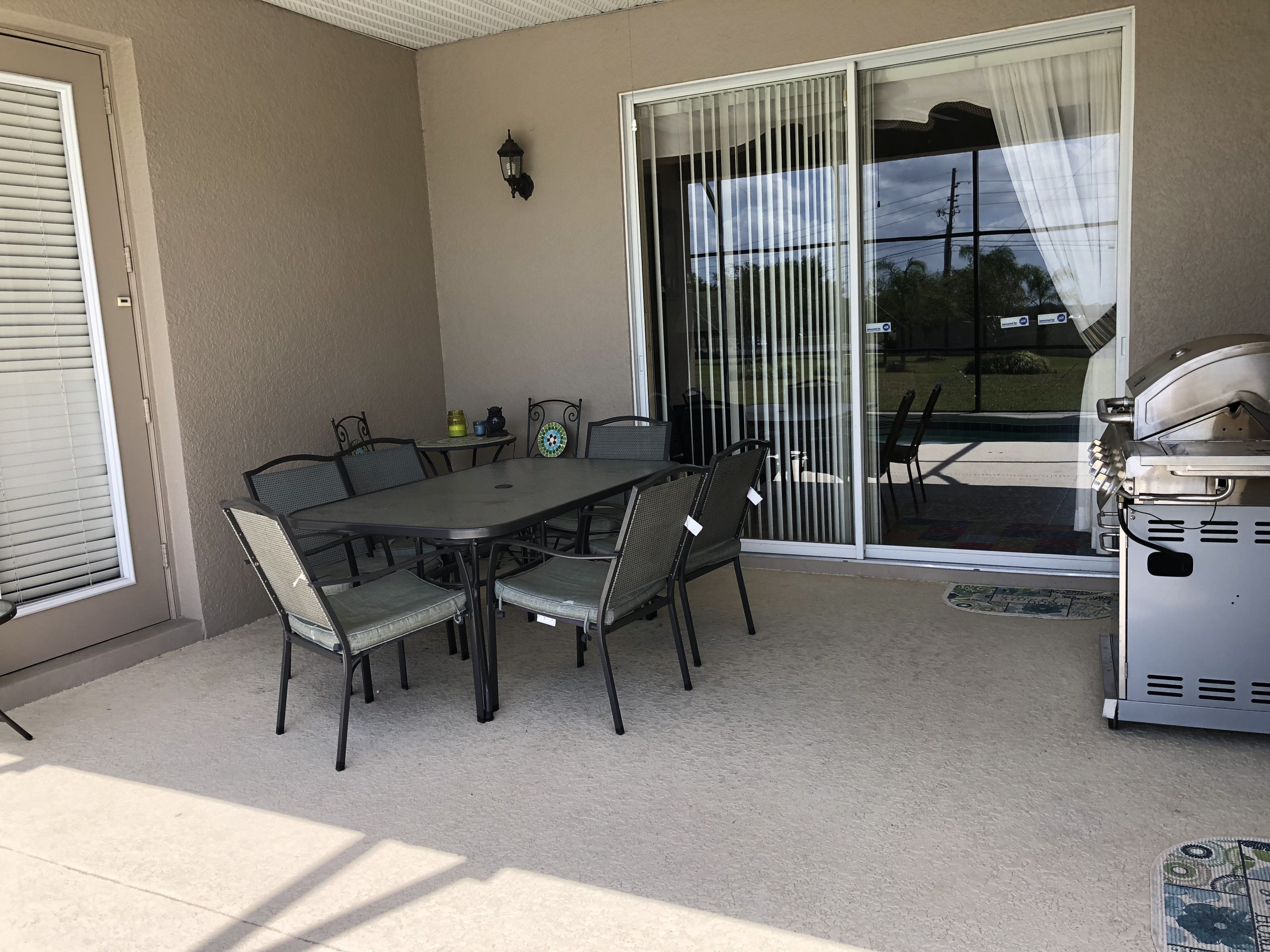 A patio with a table and chairs, a grill, and a sliding glass door.