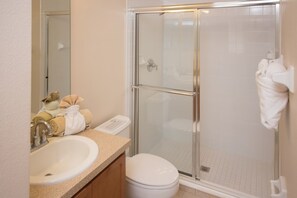A bathroom with a glass-enclosed shower, a sink, and a toilet. - The Shire at West Haven 113 (Davenport)