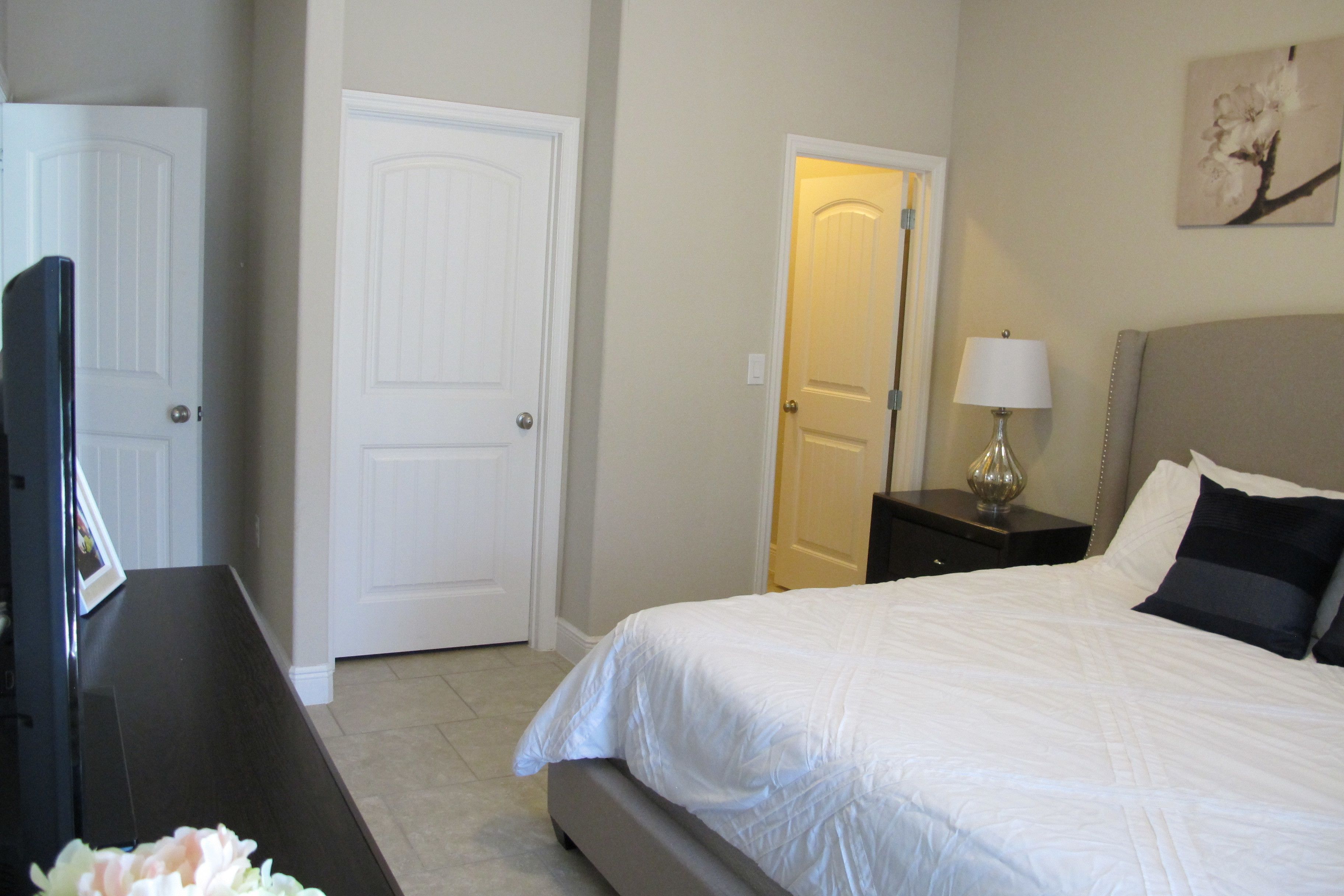 A bedroom with a bed, a nightstand, a lamp, and a door.