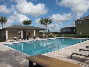 A swimming pool with a tiled deck, lounge chairs, and a covered seating area. - Laurel Estates 133 (Davenport)