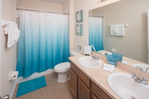 A bathroom with a shower curtain, toilet, sink, and mirror. - Laurel Estates 133 (Davenport)