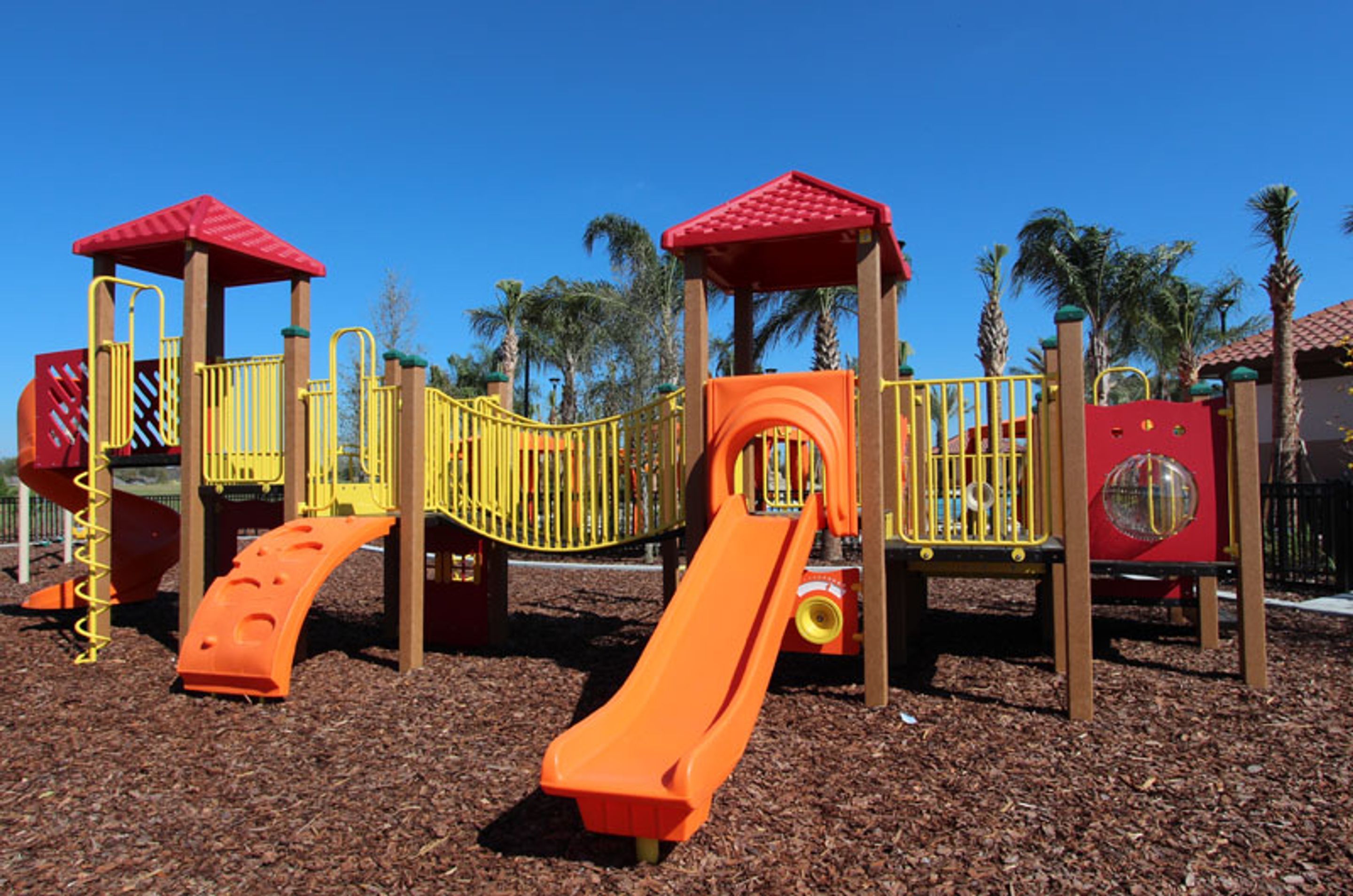 A playground with a slide, climbing structures, and a red-roofed shelter.