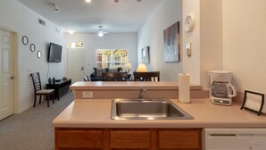 A compact kitchen with a sink, a coffee maker, and a small island with a countertop. - Villas at Seven Dwarfs 4601 B8.106 (Kissimmee)