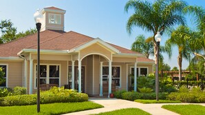 A two-story house with a covered porch, a small tower-like structure on the roof, and a well-maintained garden with palm trees and shrubs. - Lucaya Village 2905 - 101 (Kissimmee)