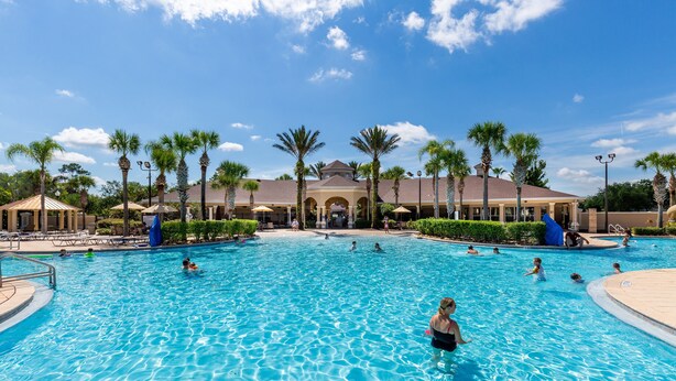 A large outdoor swimming pool with multiple lanes, surrounded by palm trees and lounge chairs. - Windsor Hills 2583 (Kissimmee)