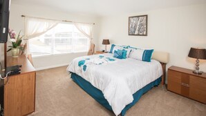 A bedroom with a bed, a desk, a lamp, and a window with curtains. - Windsor Hills 2583 (Kissimmee)