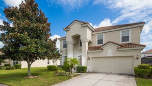 A two-story house with a white facade, a red-tiled roof, and a garage. - Windsor Hills 2583 (Kissimmee)