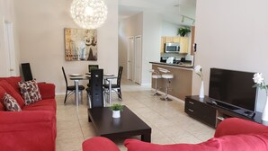 A modern living room with red sofas, a dining table, and a kitchen area in the background. - Sandy Ridge 922 (Davenport)