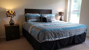 A bedroom with a large bed, dark headboard, and patterned bedding. There are two bedside tables with lamps and vases. - Sandy Ridge 922 (Davenport)