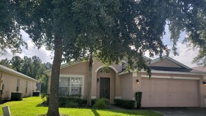 A residential house with a garage, a well-maintained lawn, and a large tree in the front yard. - Sandy Ridge 922 (Davenport)