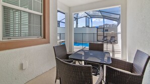A patio with wicker furniture, a pool, and a covered area with chairs. - Storey Lake 4953 (Kissimmee)