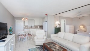Un salon moderne avec un canapé blanc, une table basse et un coin repas comprenant une table et des chaises blanches.