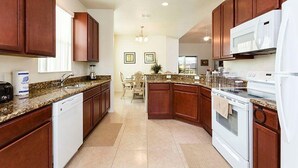 Una cocina moderna con gabinetes de madera, encimeras de granito, lavavajillas, estufa y microondas.