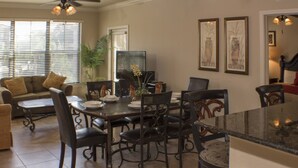 A dining area with a wooden table and chairs, a sofa, and a plant. - Bella Piazza 904 - 527 (Davenport)