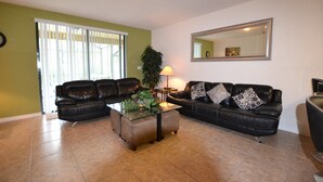A living room with two black leather sofas, a glass coffee table, and a large mirror on the wall. - Cypress Pointe 1151 (Davenport)