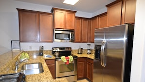 A kitchen with wooden cabinets, stainless steel appliances, granite countertops, and a built-in oven. - Cypress Pointe 1151 (Davenport)