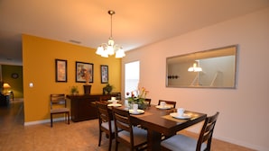 A dining area with a wooden table set for four, surrounded by chairs. There is a chandelier above the table, and a large mirror on the wall. - Cypress Pointe 1151 (Davenport)
