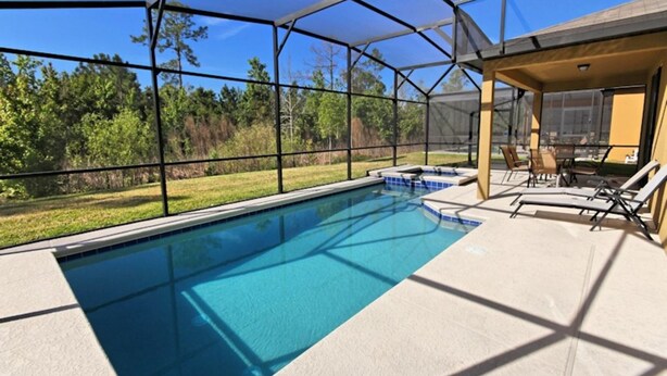 A swimming pool with a covered area, surrounded by a fence, and a patio with chairs and a table. - Cypress Pointe 1151 (Davenport)