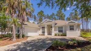 A two-story house with a front driveway, palm trees, and a well-maintained lawn. - Highlands Reserve Golf & Country Club 520 (Davenport)