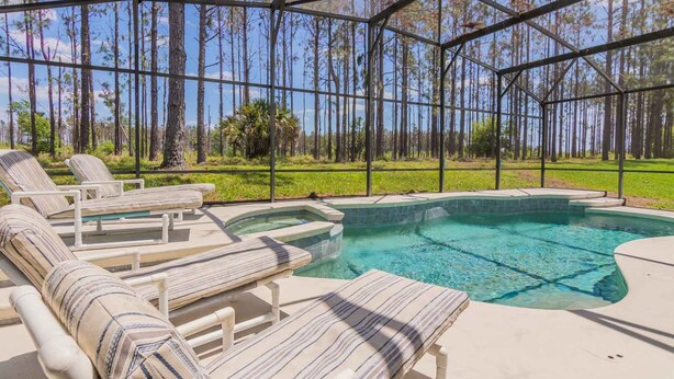 A covered outdoor swimming pool with lounge chairs, surrounded by a forested area. - Highlands Reserve Golf & Country Club 520 (Davenport)