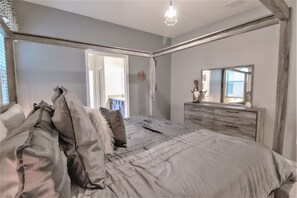 A bedroom with a bed, dresser, and a mirror. - Windsor at Westside 1852 (Kissimmee)