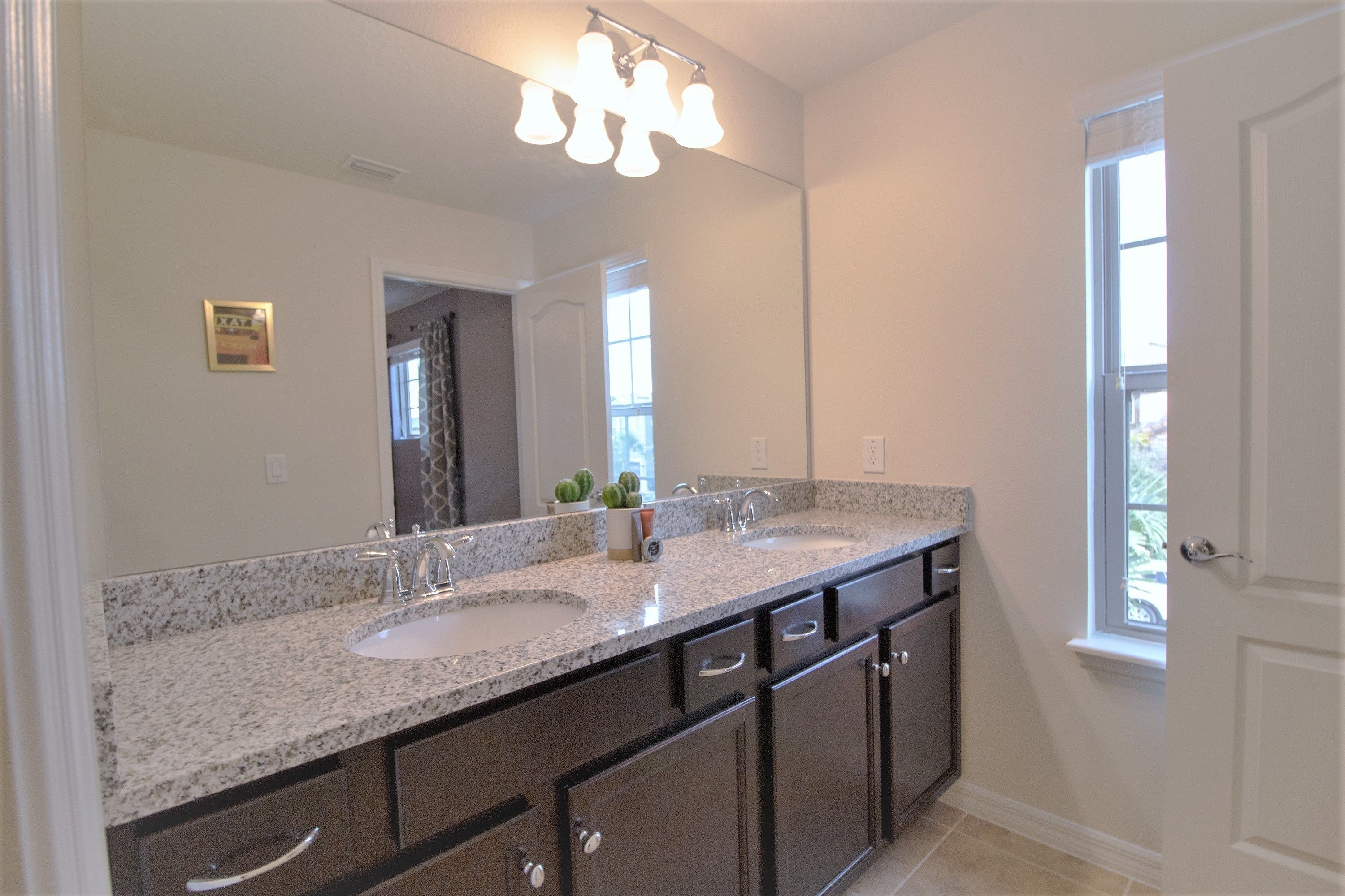 A bathroom with two sinks, a large mirror, and a light fixture above.