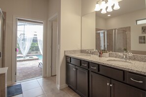 A modern bathroom with a large sink, dark cabinets, and a glass shower enclosure. - Windsor at Westside 1852 (Kissimmee)
