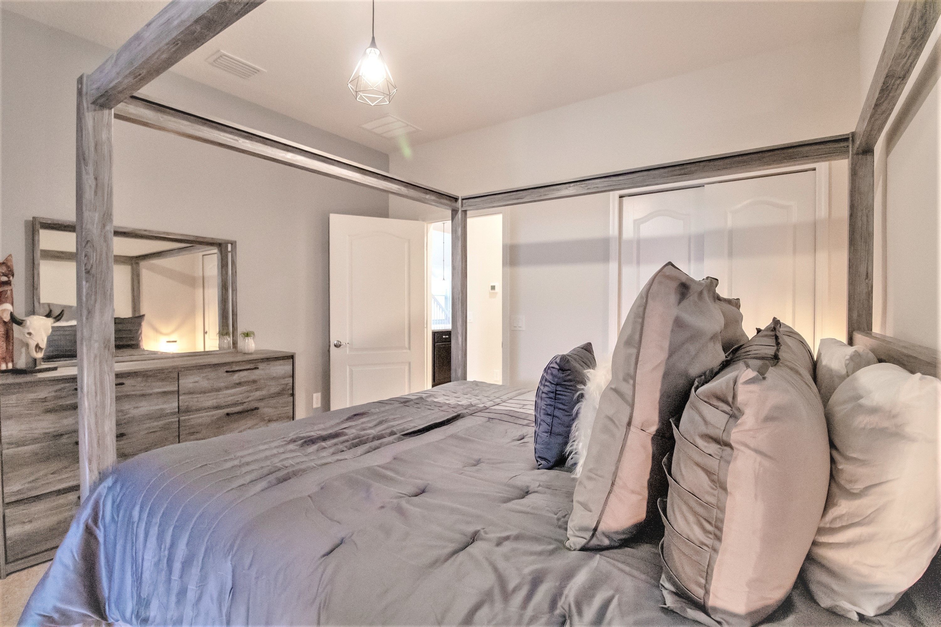 A bedroom with a large bed, a wooden headboard, a dresser, and a mirror.