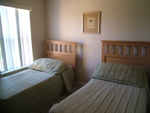Two single beds with wooden headboards in a room with a window and a framed picture on the wall. - Regal Palms Resort & Spa 117 (Davenport)
