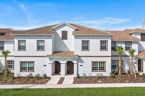 A two-story residential building with a tiled roof, a central entrance with a door, and a small porch area. - Storey Lake 4947 (Kissimmee)
