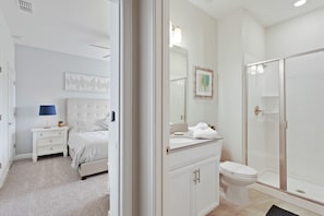 A modern bathroom with a walk-in shower, a toilet, and a vanity with a mirror. - Storey Lake 4947 (Kissimmee)