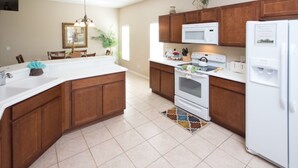 A kitchen with wooden cabinets, a white countertop, a microwave, a stove, and a refrigerator.