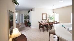 A dining area with a table set for four, surrounded by chairs. There is a white countertop with a sink and a mirror above it.