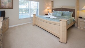 A bedroom with a bed, a nightstand, a dresser, a window, and a painting on the wall.