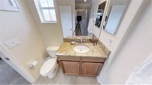 A bathroom with a toilet, sink, vanity, and mirror. - Paradise Palms 3073 (Kissimmee)