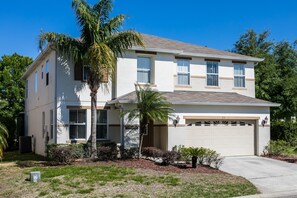 A two-story residential building with a garage, a palm tree, and a well-maintained lawn. - Legacy Park 212 (Davenport)