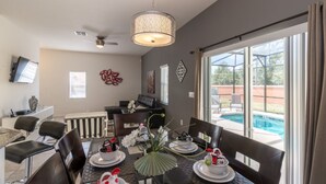 A dining area with a pool view, a ceiling fan, and a TV mounted on the wall. - Bella Vida 1300 (Kissimmee)