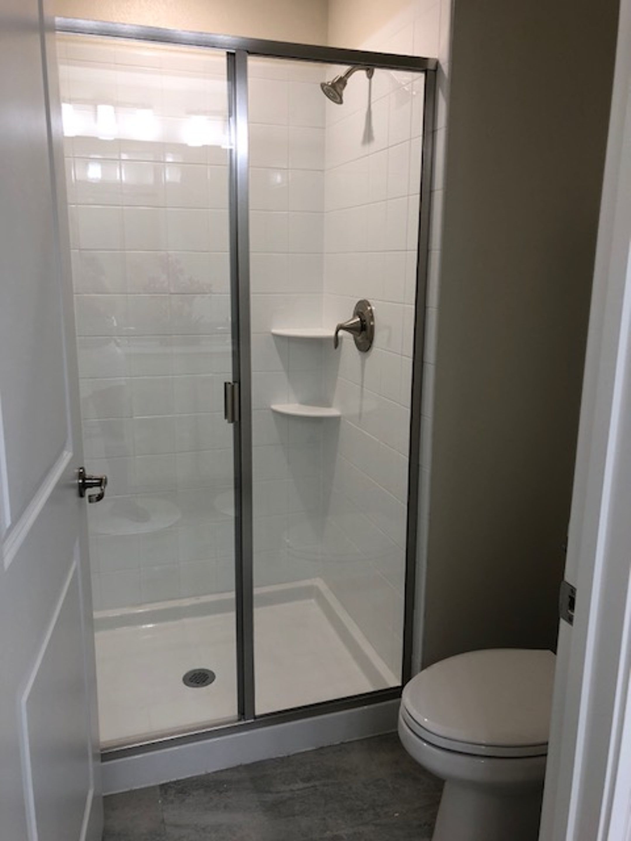 A bathroom with a glass-enclosed shower, a toilet, and a sink.