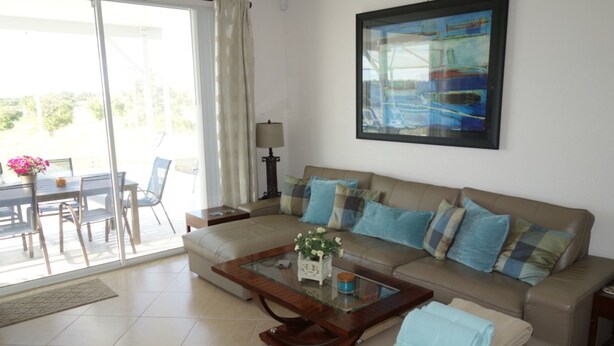 A living room with a sofa, coffee table, and a painting on the wall. - Highlands Reserve Golf & Country Club 303 (Davenport)