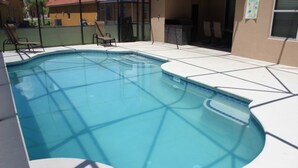 A swimming pool with a geometric tile pattern, surrounded by lounge chairs and a covered seating area.