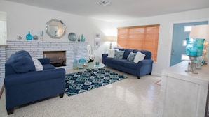 A living room with two blue sofas, a patterned rug, a fireplace, and a door with a window. - Fort Myers Beach Area 540 (Fort Myers)