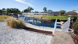 A marina with boats docked, a covered walkway, and a grassy area with palm trees. - Fort Myers Beach Area 540 (Fort Myers)