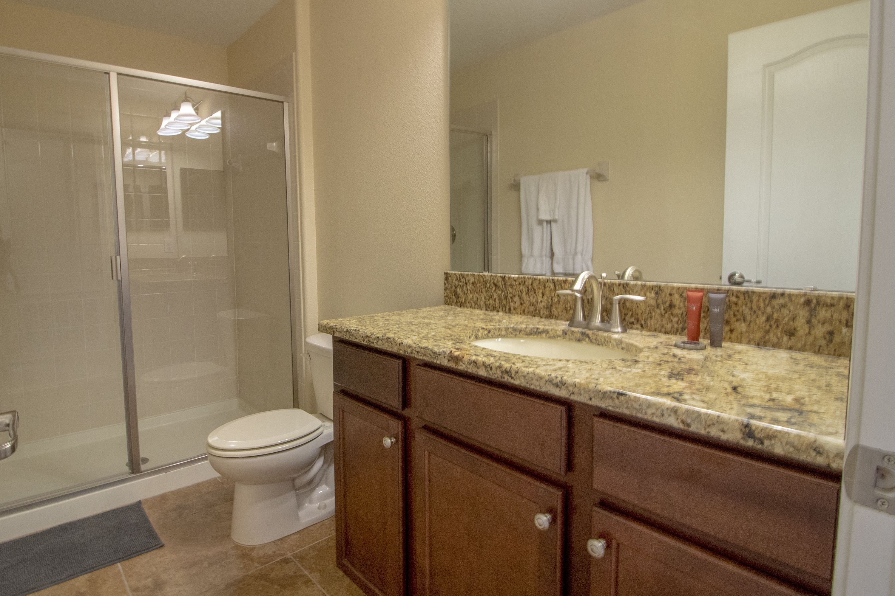 A bathroom with a shower, toilet, sink, and vanity.